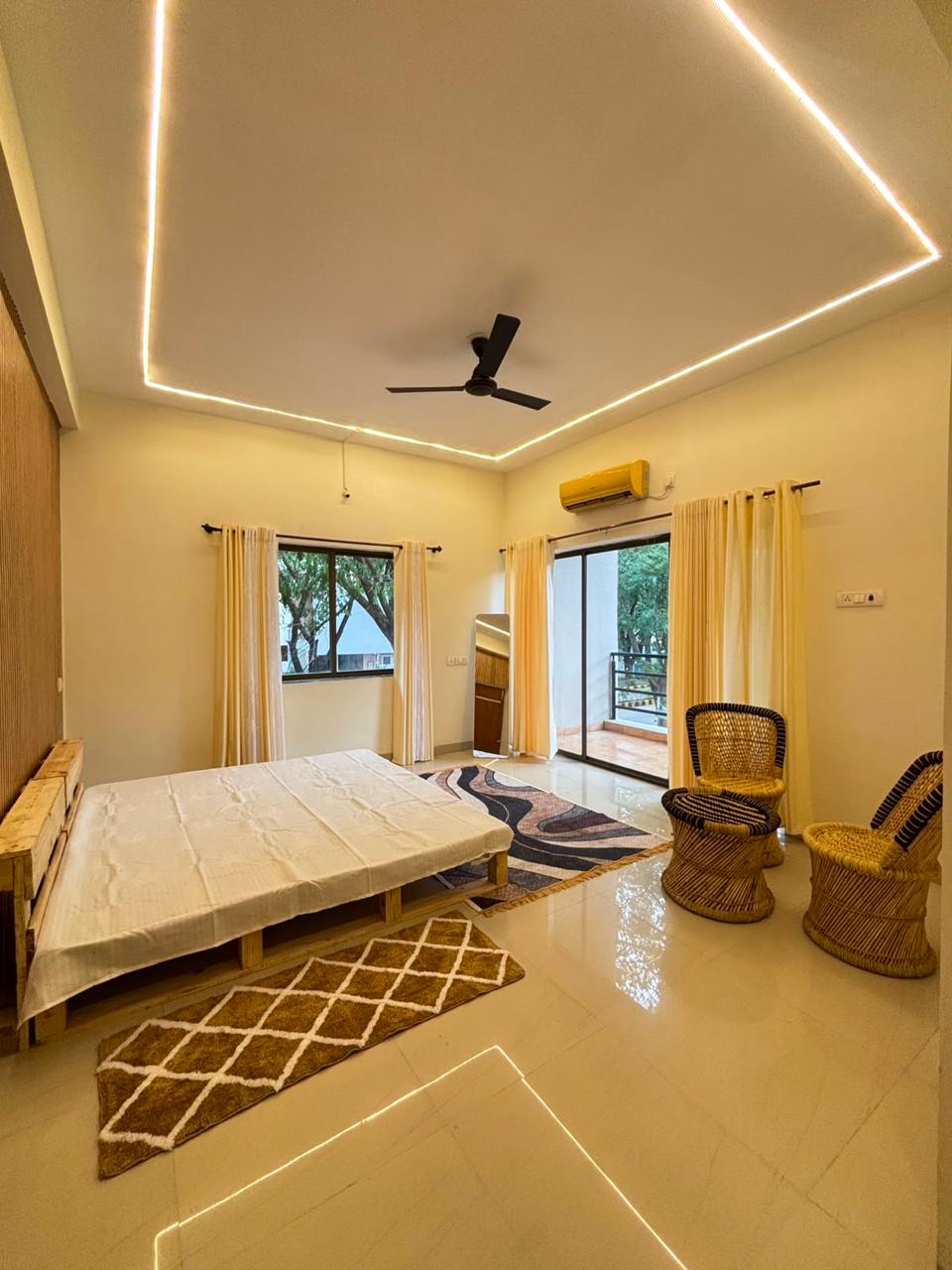 Bedroom with pallet-style bed, rattan chairs, and private balcony