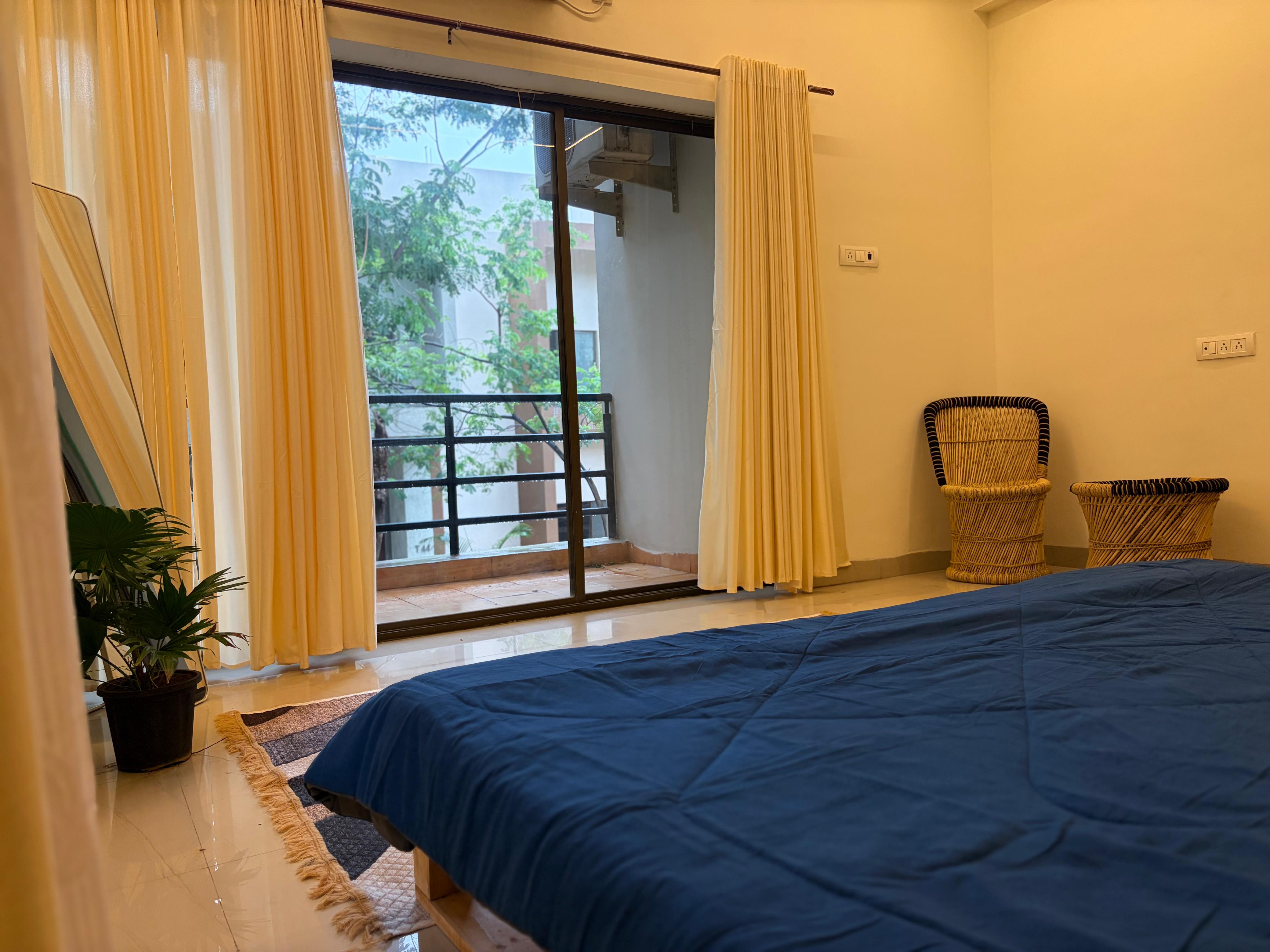 Bedroom with rattan chairs and balcony seating area
