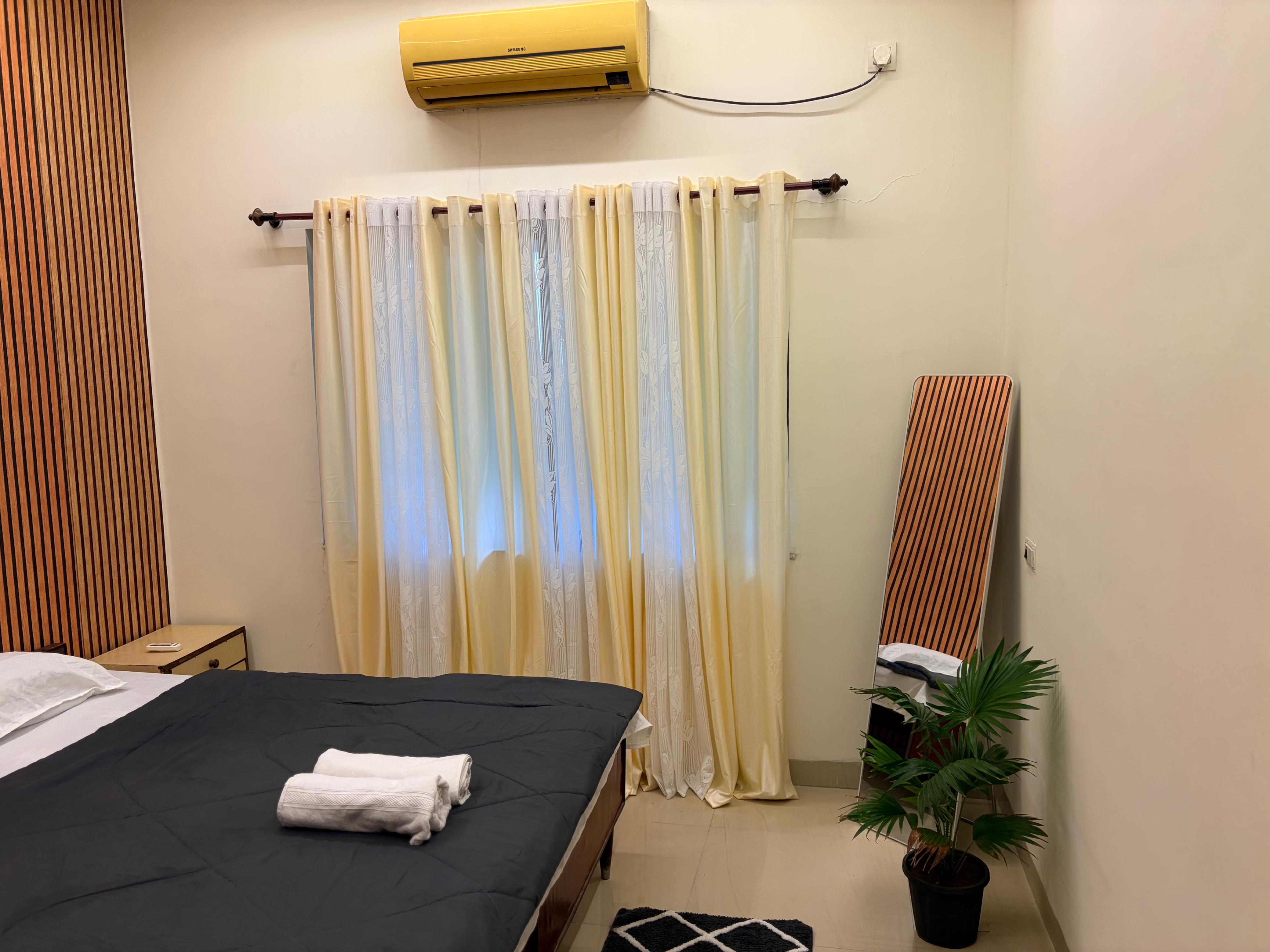 Bedroom with charcoal bedspread, fresh towels, and mirror